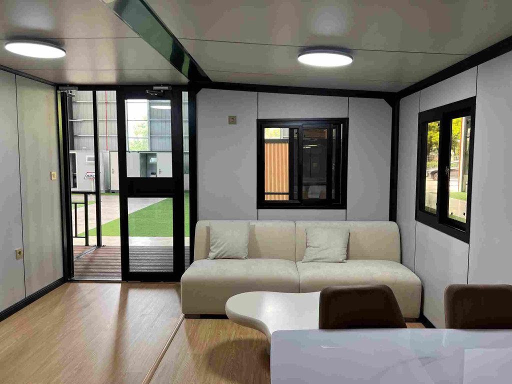 Modern living room inside expandable container home with dining area and terrace access
