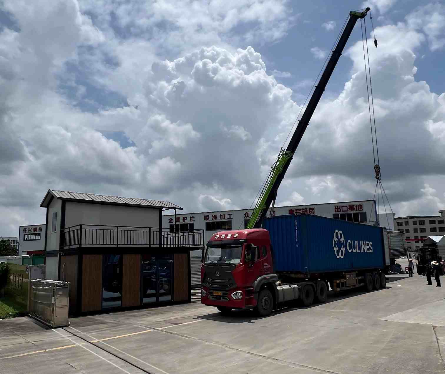 Crane loading modular container house onto shipping container at steel structure factory